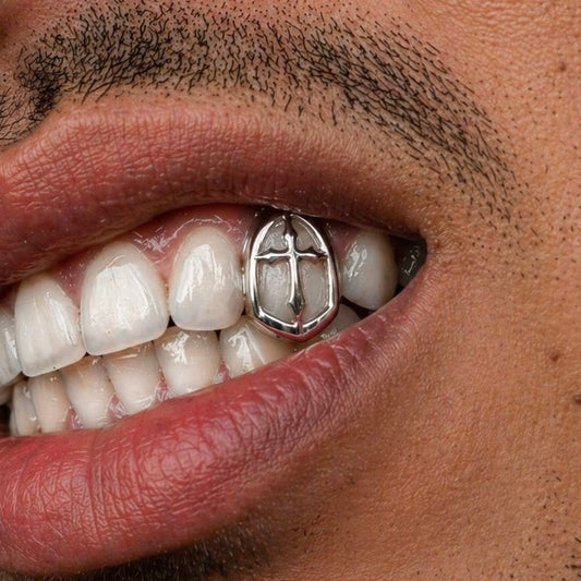 Close-up of a person's mouth with a silver grill on their teeth.